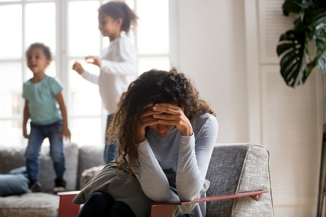 Stressed out mother with two kids in the background